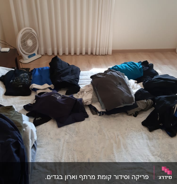 בגדים מקופלים על מיטה בחדר שינה